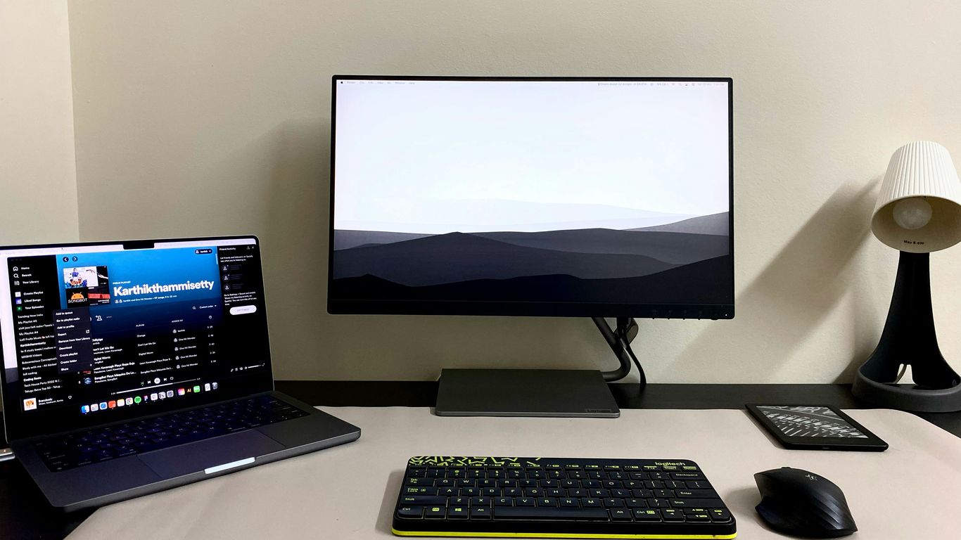 a desk with a laptop, keyboard, mouse and monitor