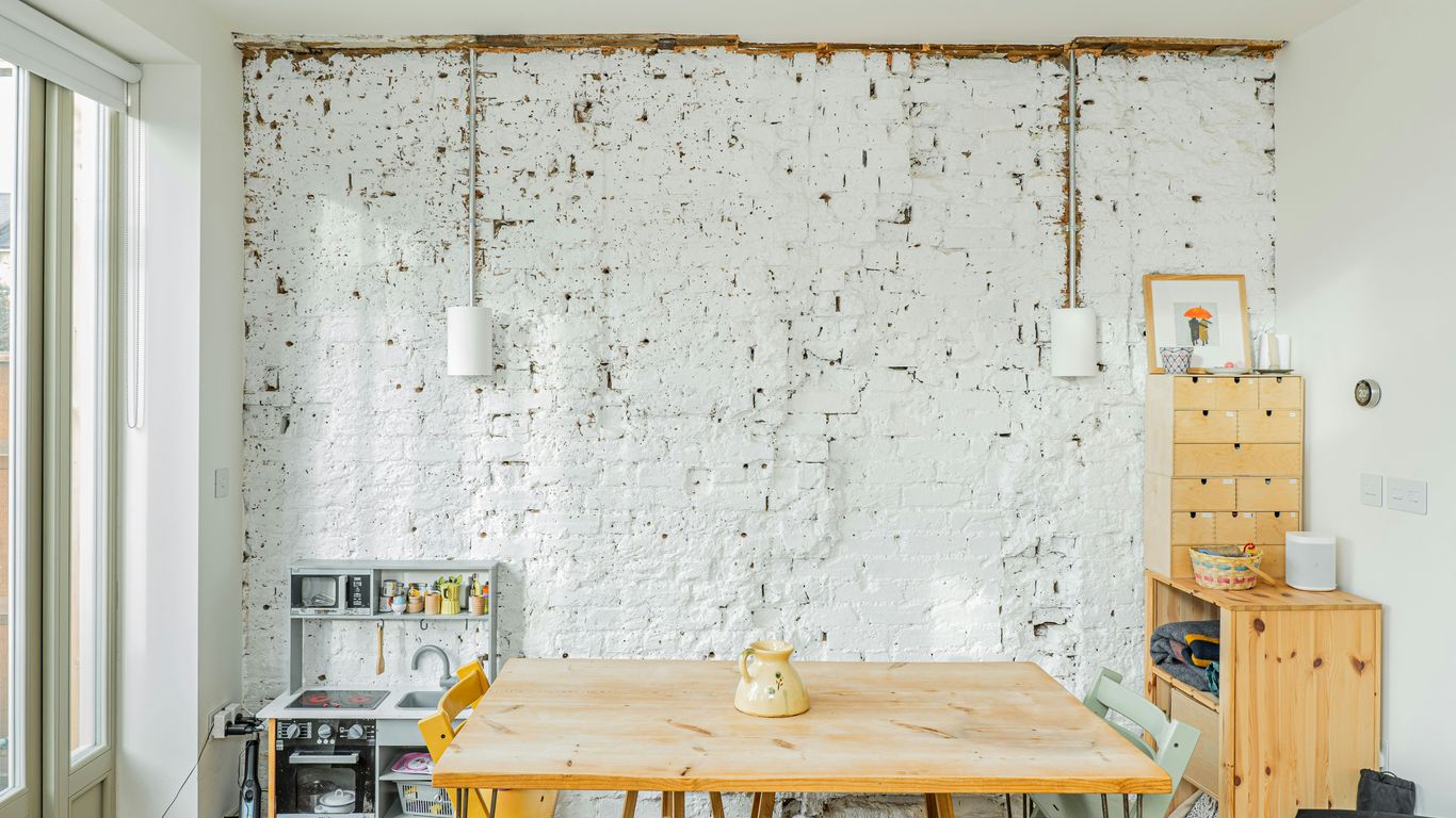 A room with a wooden table and a white brick wall