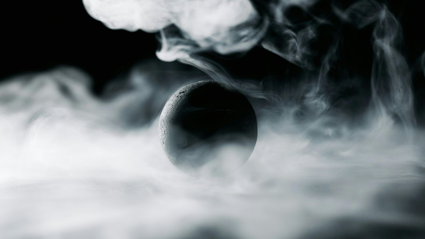 Dark sphere surrounded by swirling white smoke, mysterious atmosphere.