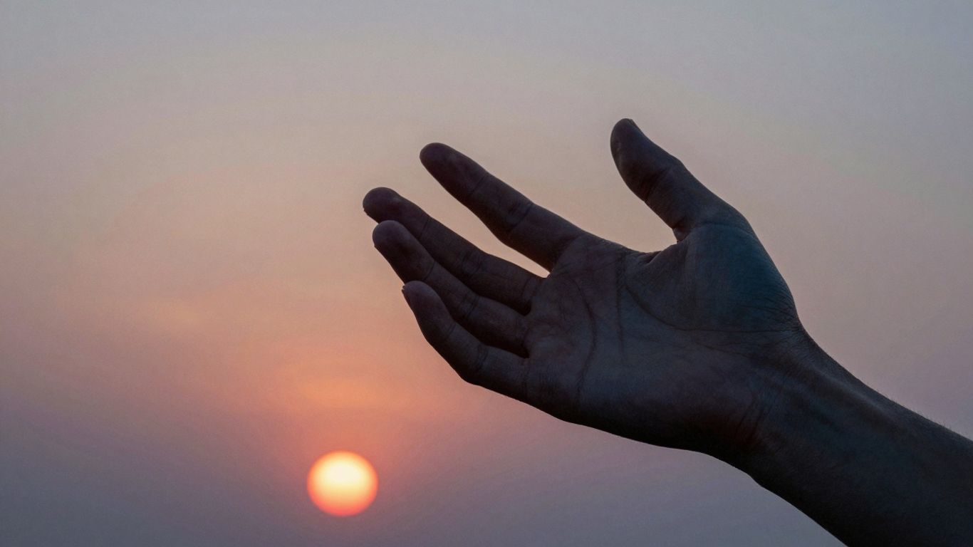 Hand touching a vibrant, colorful sunset sky.