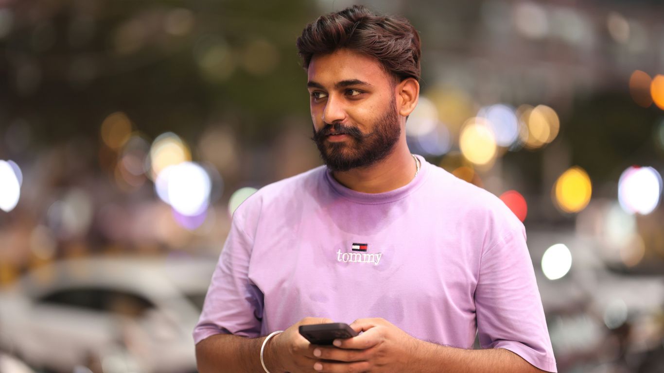 A man standing on a street holding a cell phone