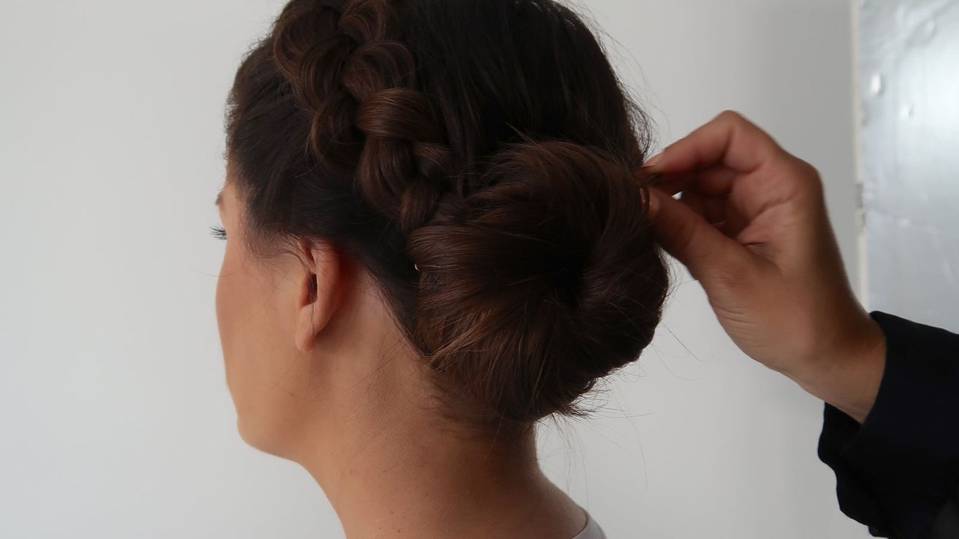 Elegant braided updo hairstyle being styled on a woman.