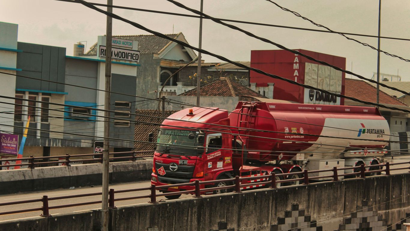 a red truck driving down a street next to a tall building