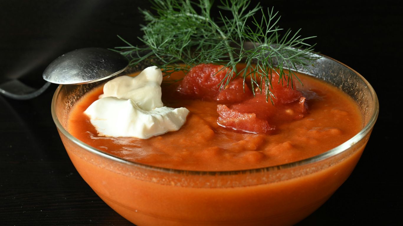 A bowl of tomato soup with a spoon