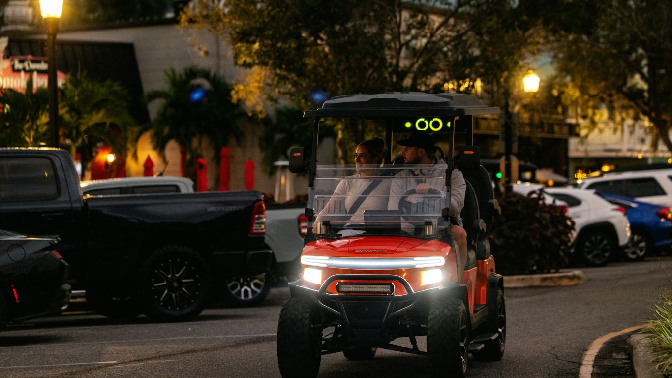 A man driving a golf cart down a street