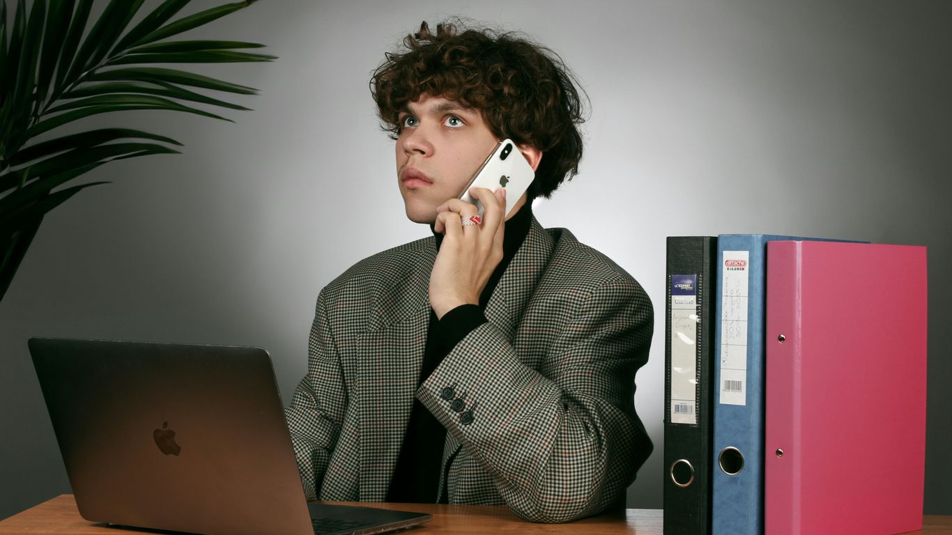 a man sitting at a desk talking on a cell phone