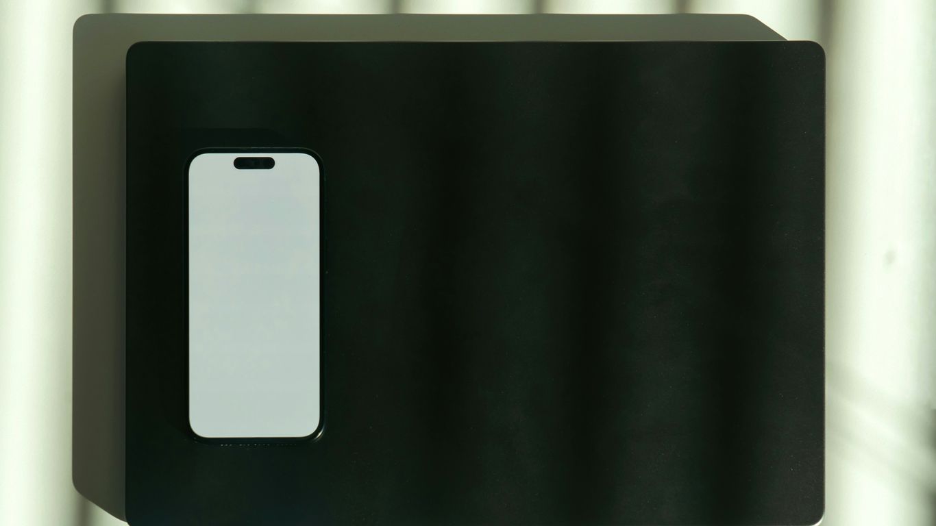 A white smartphone is placed on a black surface.