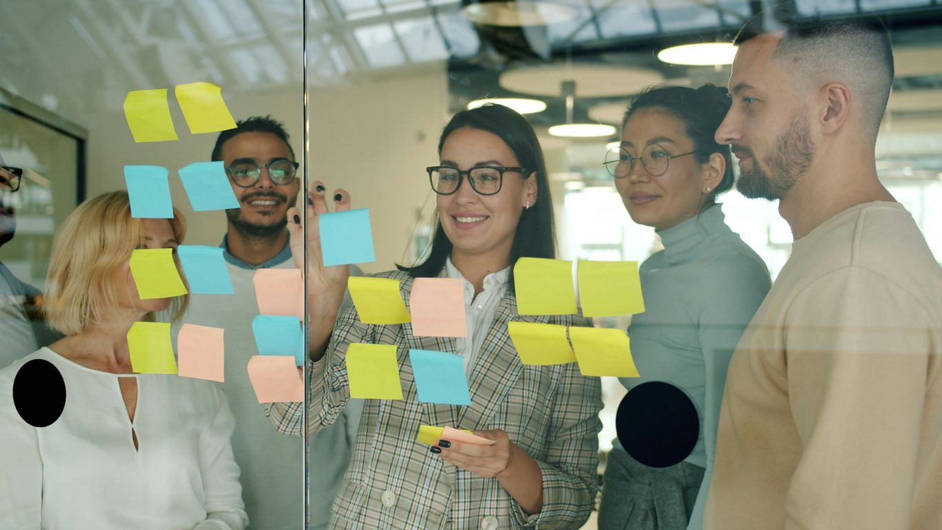 Team collaborating with sticky notes on glass wall