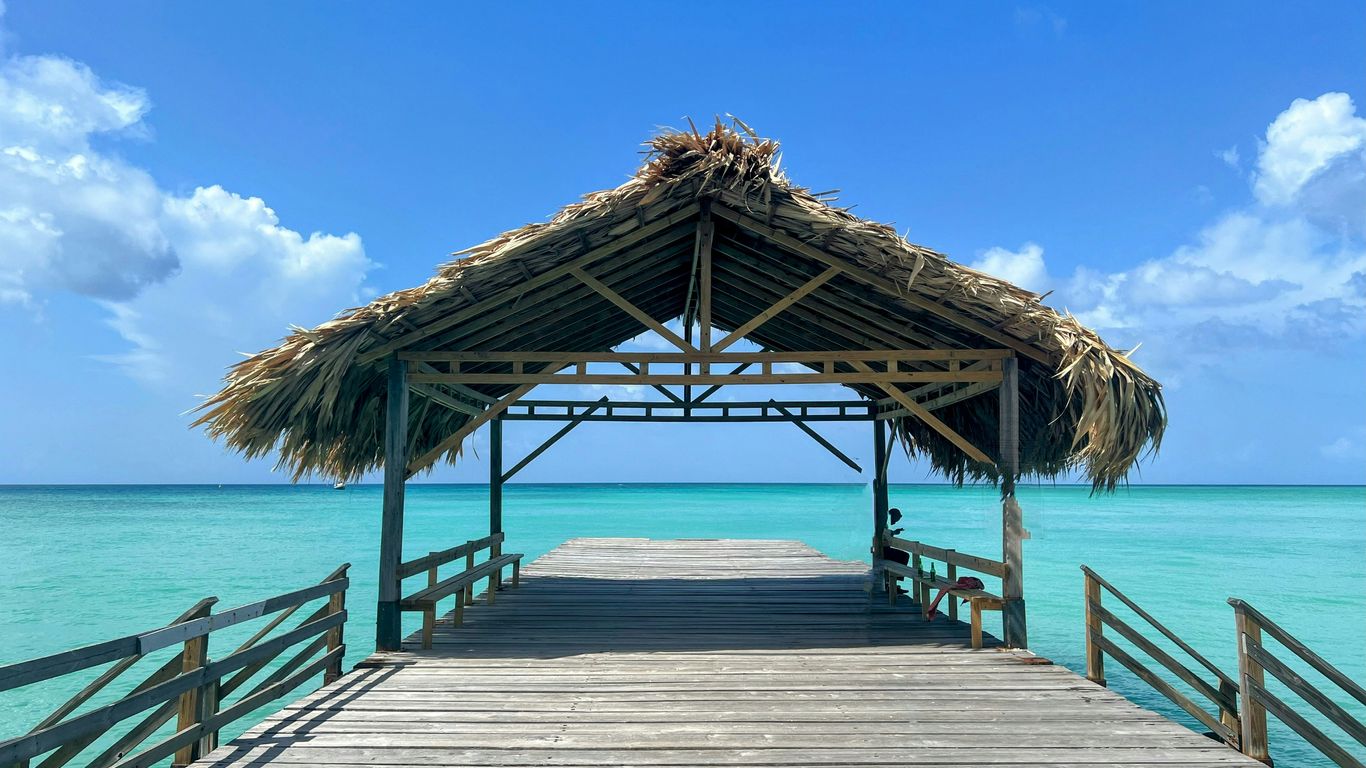 a wooden pier with a thatched roof over the ocean