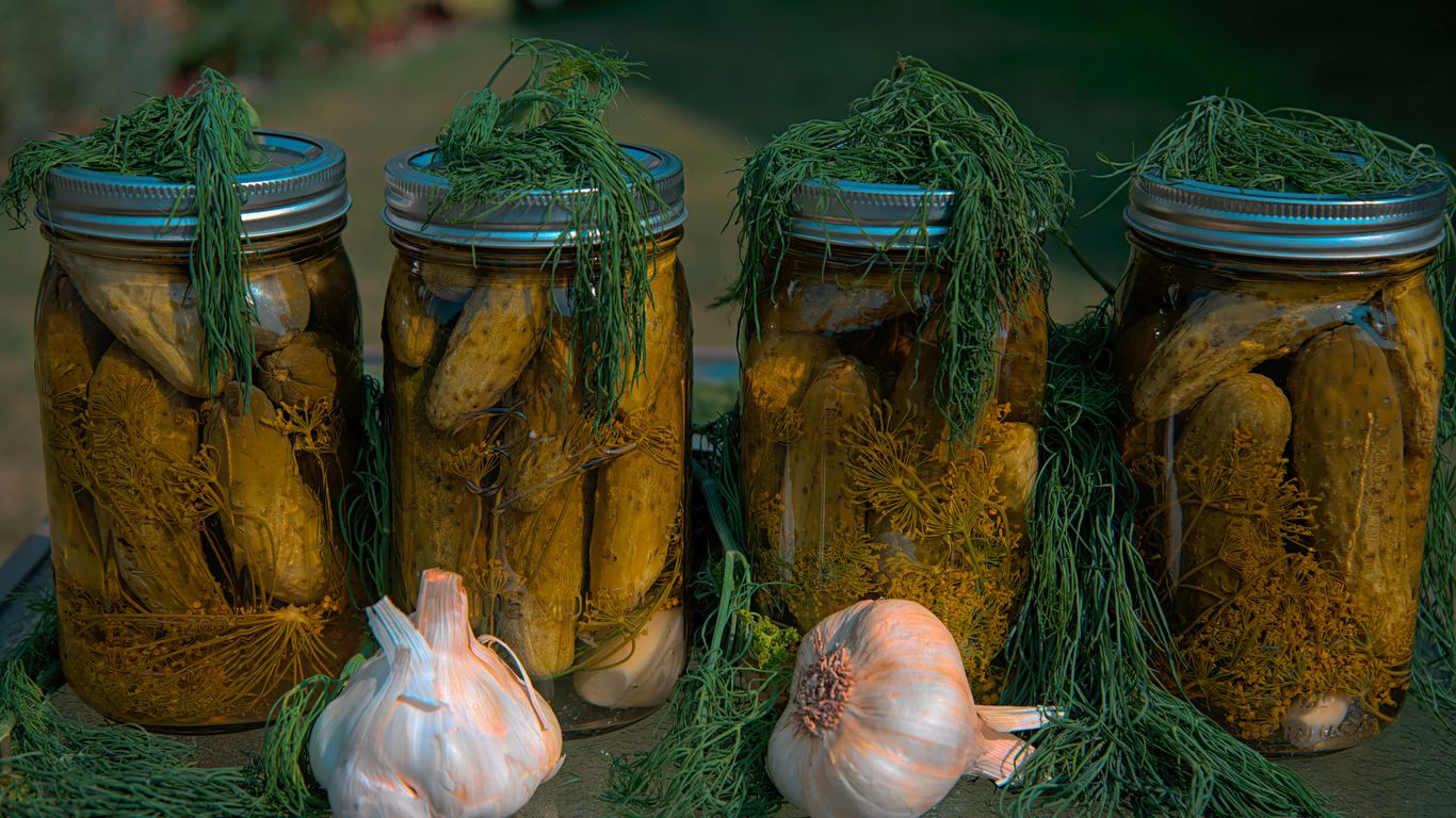 white garlic and green vegetable in clear glass jar
