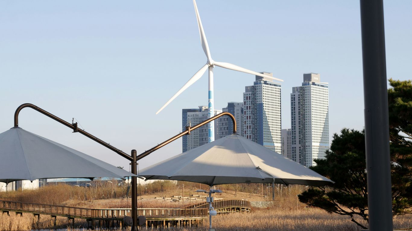 Wind turbine and modern buildings by the water.