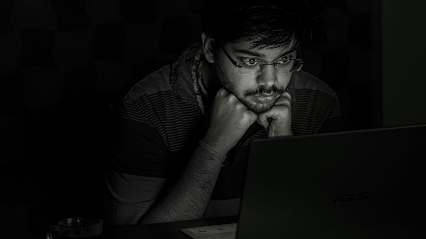 man in black and white striped shirt using black laptop computer