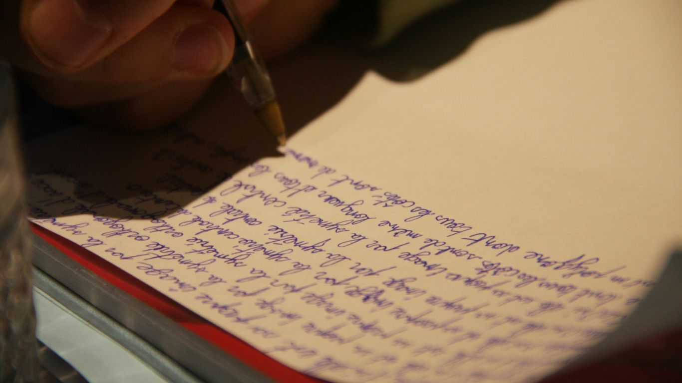 a person writing on a piece of paper with a pen