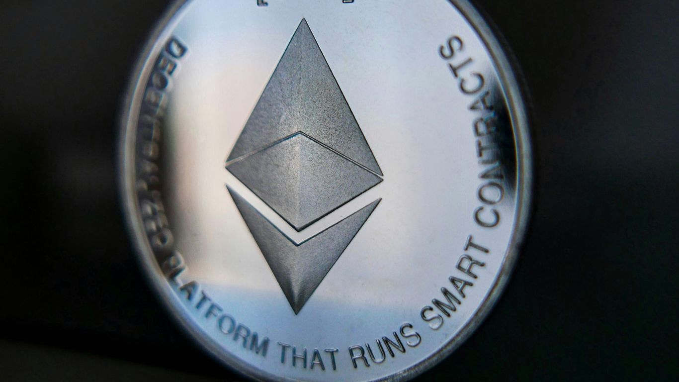 Silver Ethereum coin reflecting on a dark surface.