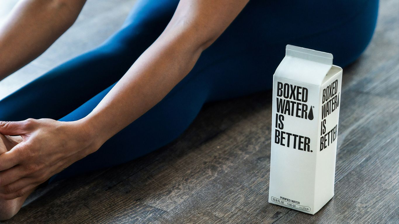 person wearing blue leggings sitting near boxed water