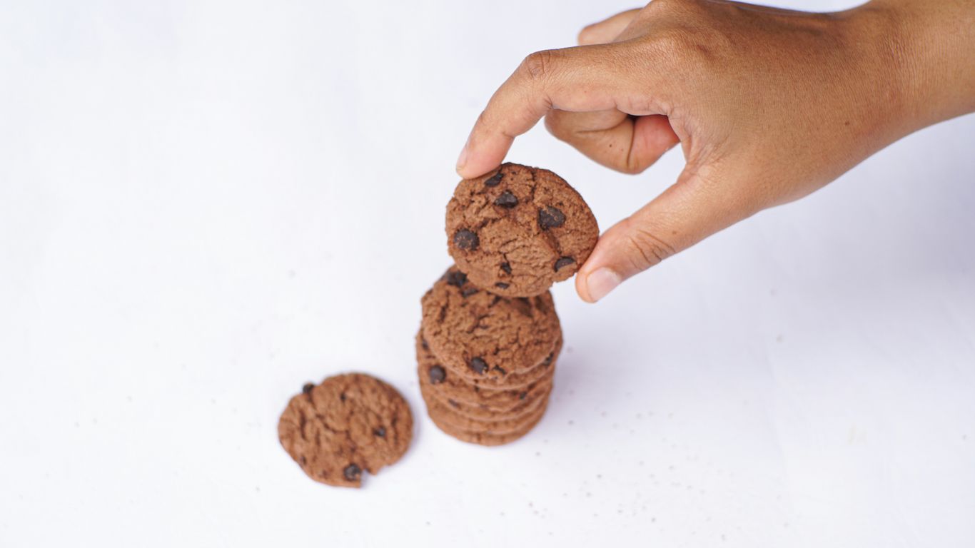 Hand is stacking chocolate chip cookies.