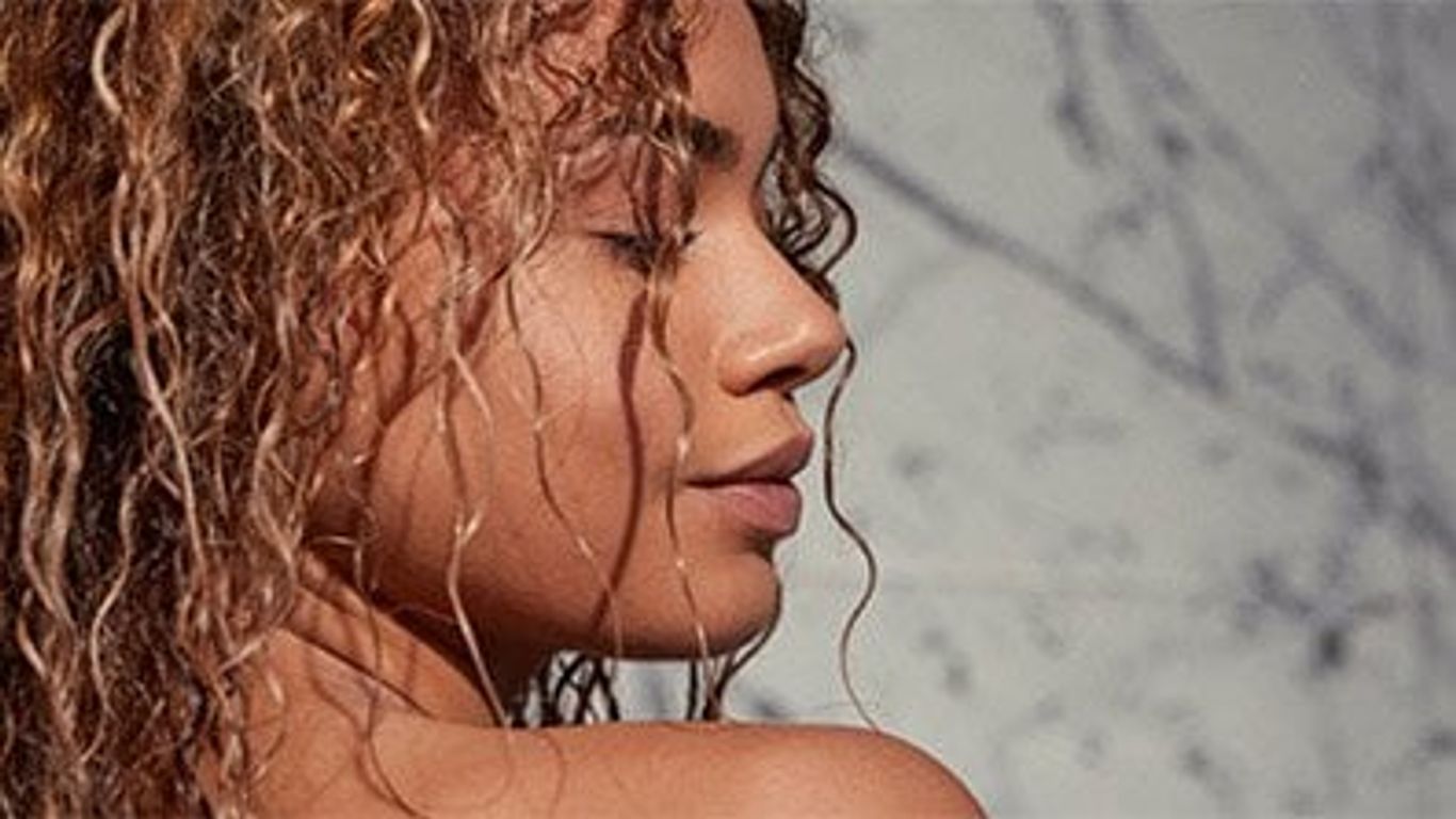 Close-up of person with curly hair, serene expression, profile view.