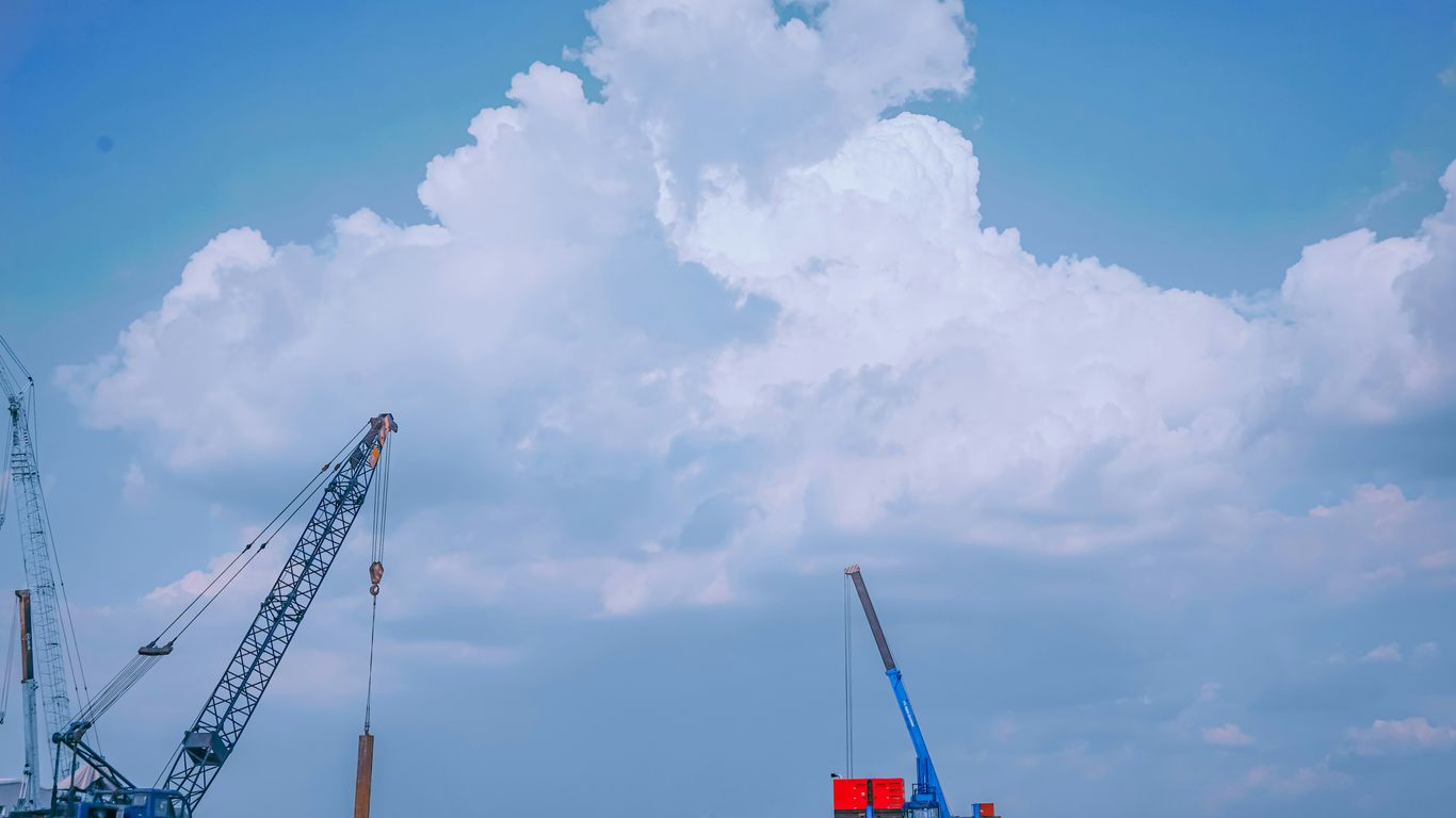 red and white crane under blue sky during daytime