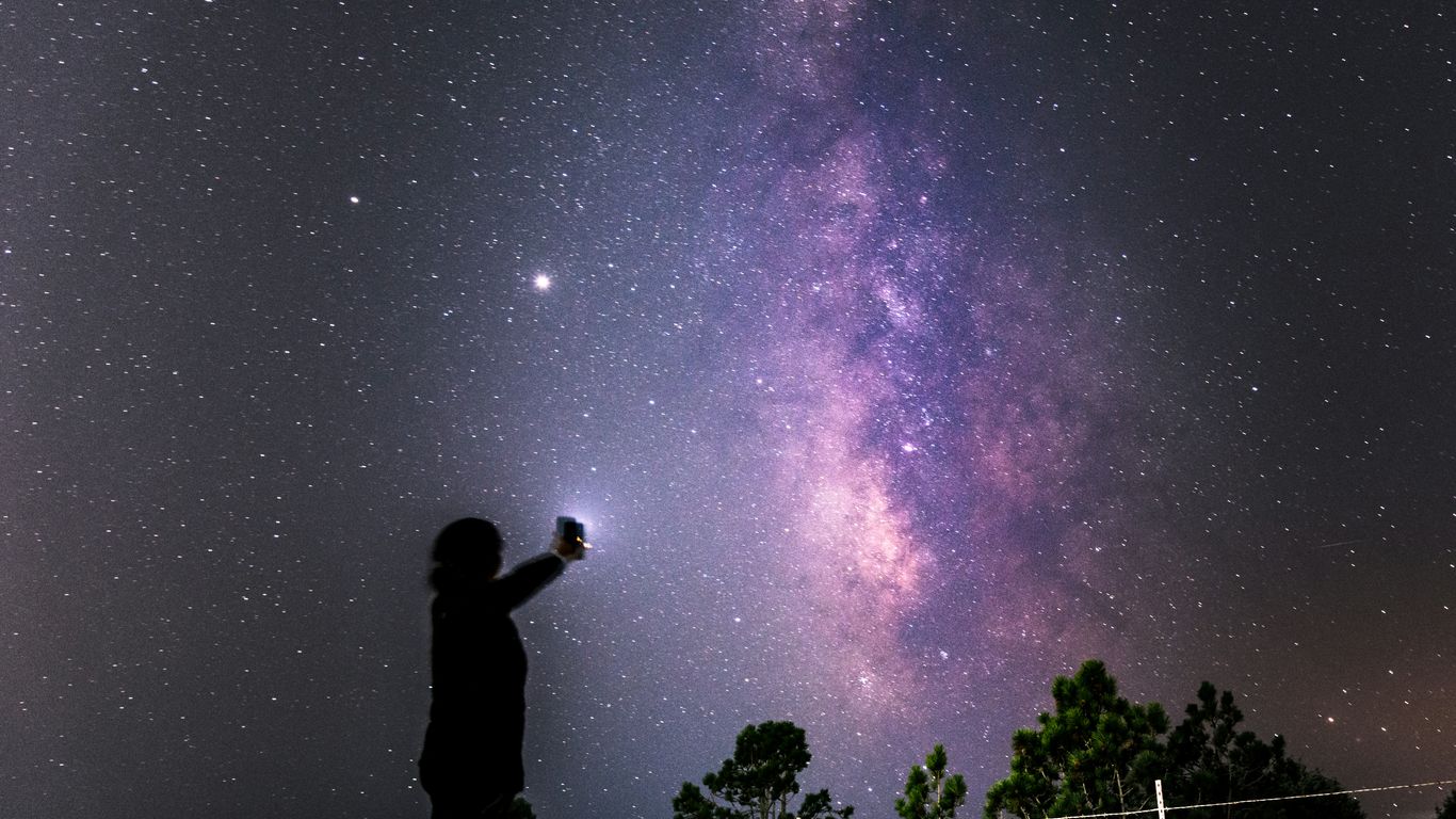 silhouette of man standing on fence under starry night