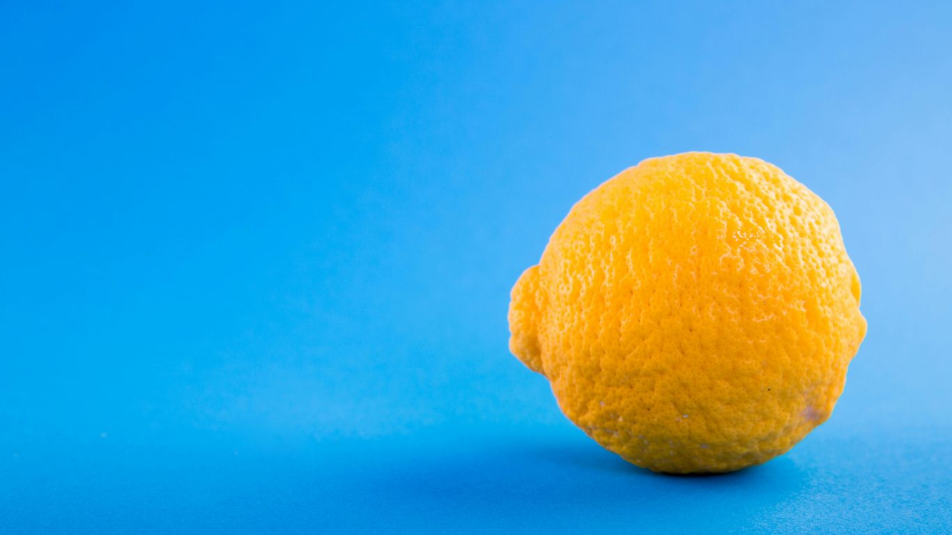 A single yellow lemon on a bright blue background.