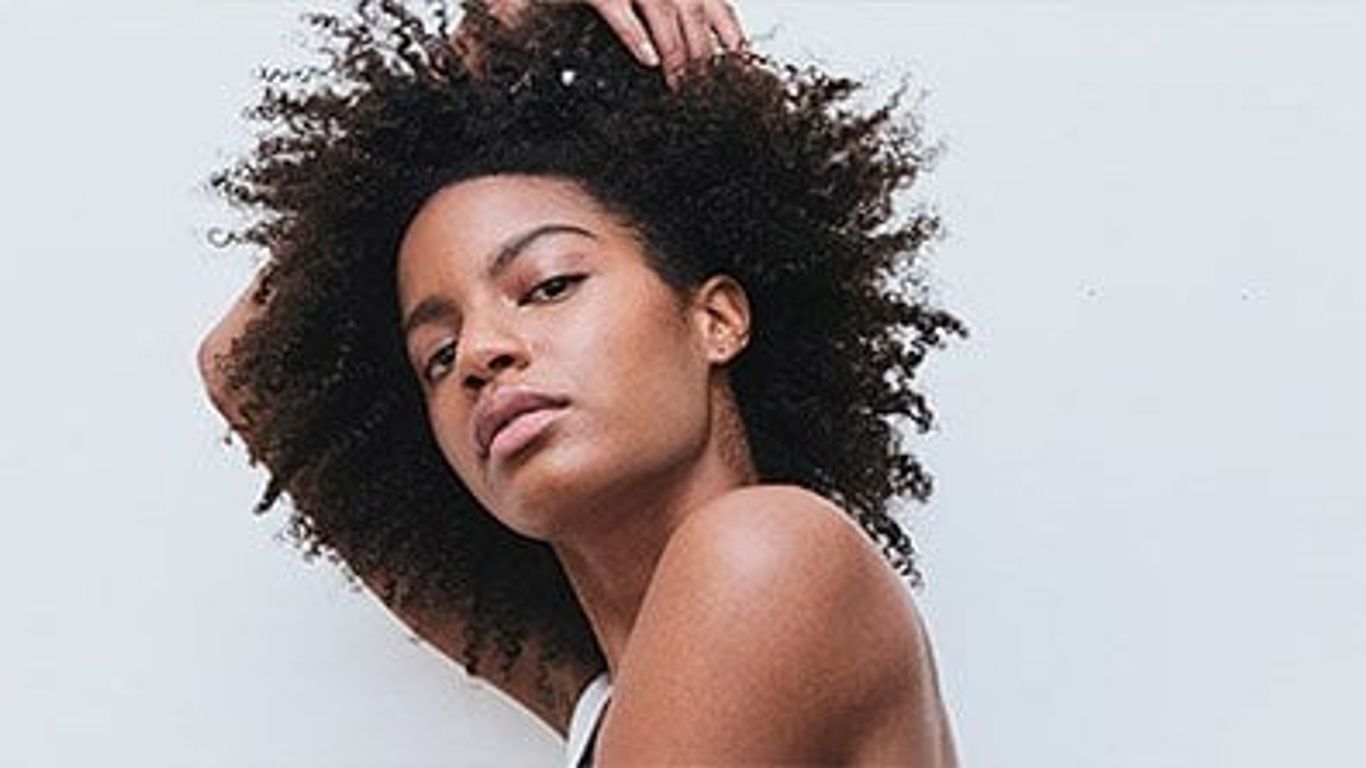 Person with voluminous hair against a plain background.