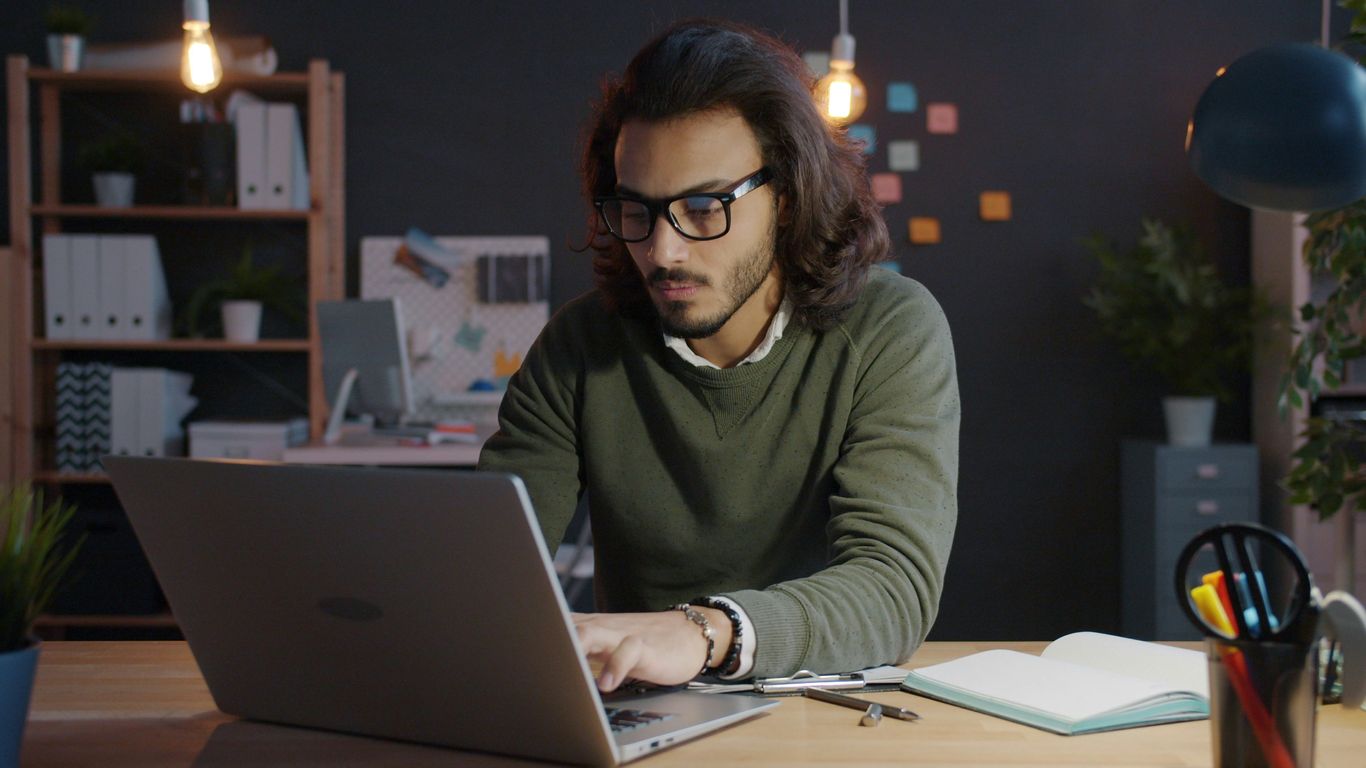 Man working on laptop in dimly lit office