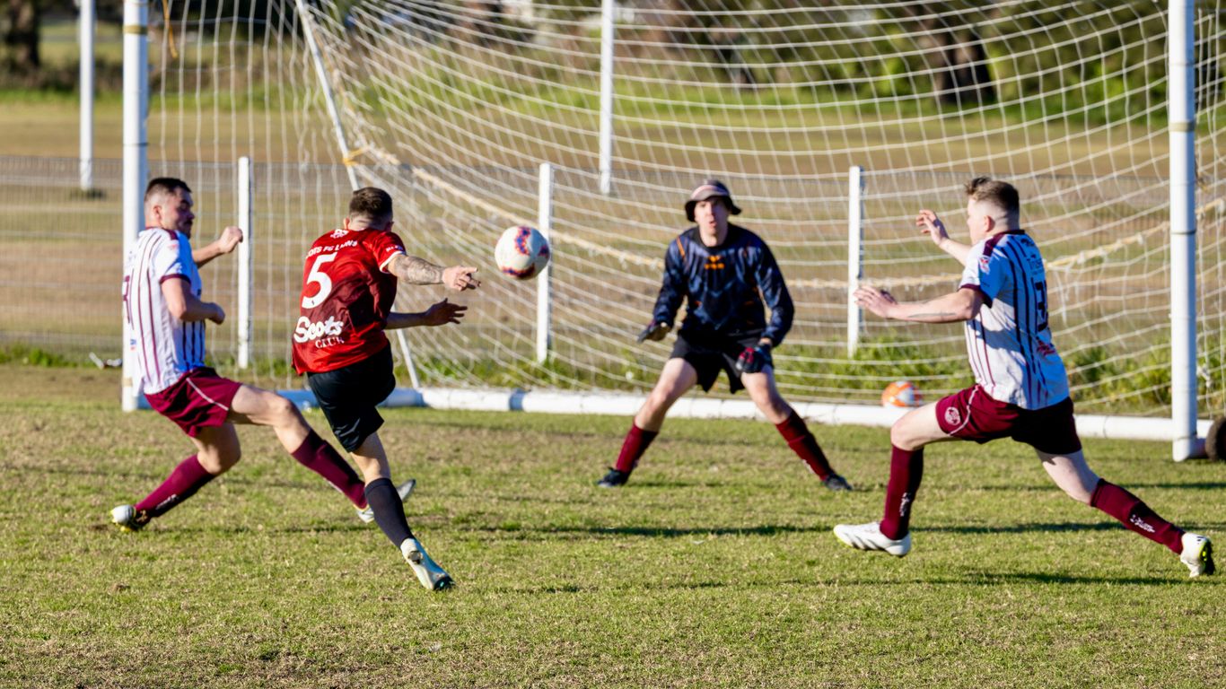 Soccer players competing for the ball near the goal.