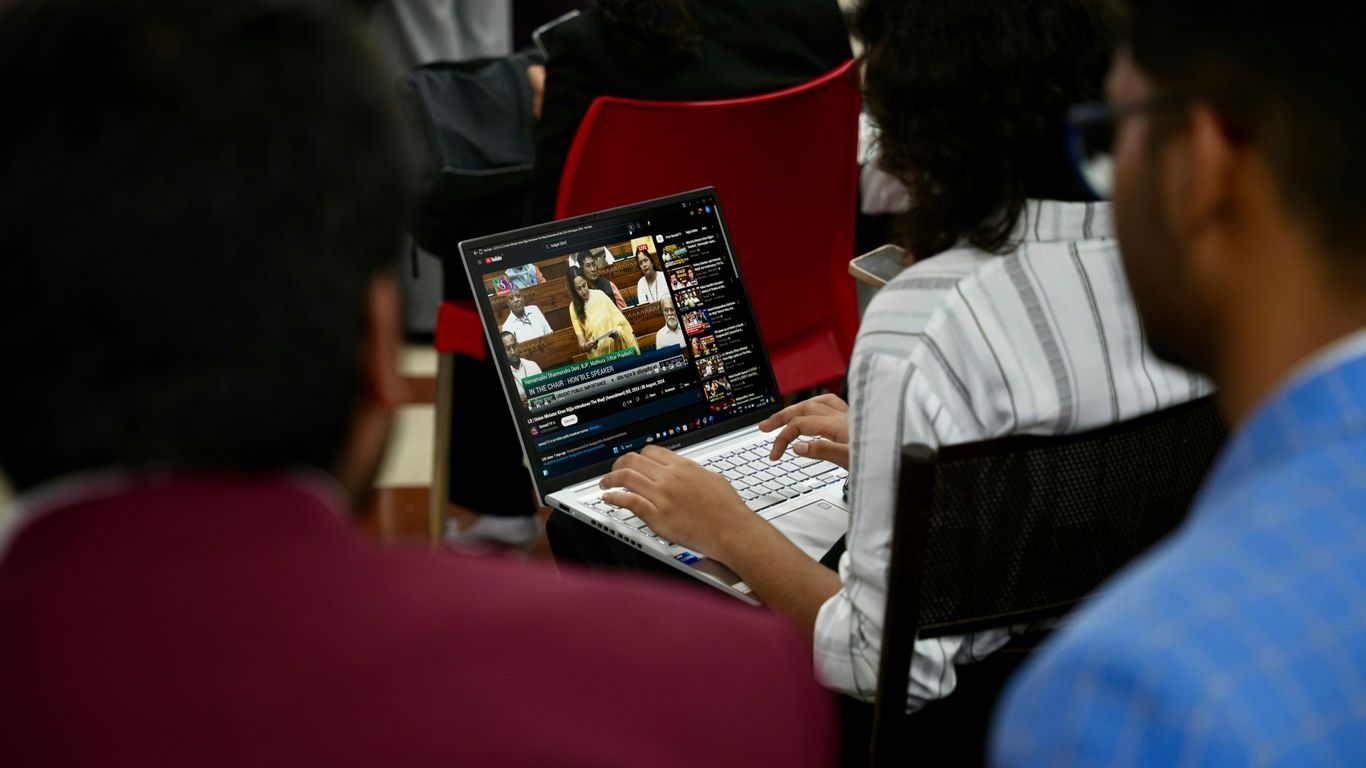 A group of people sitting around a table with laptops