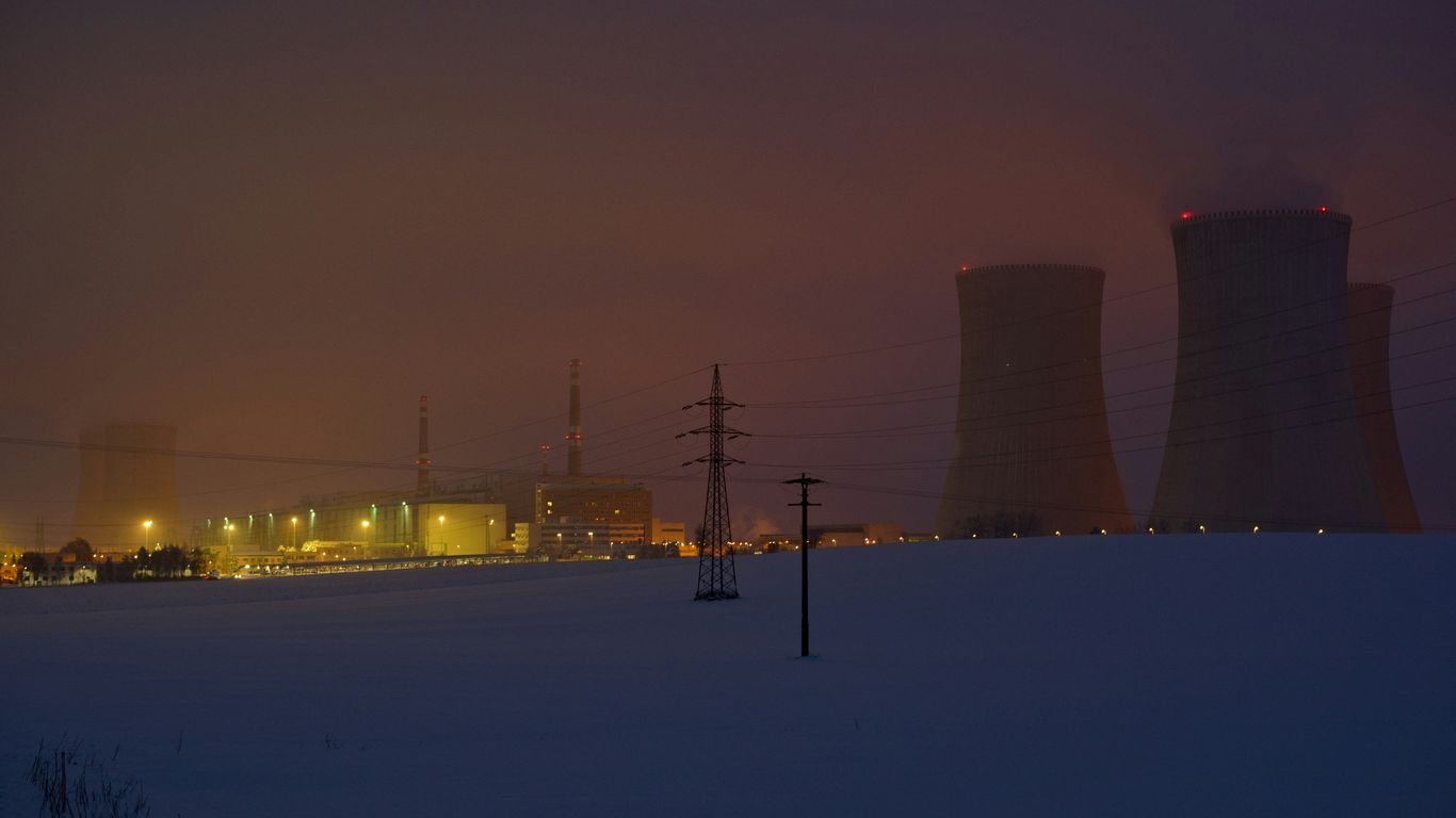 a snowy field with power lines and power plant in the background