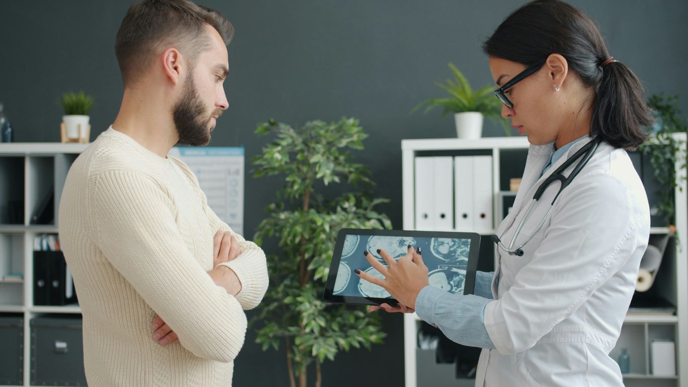 Doctor shows patient medical scan on tablet.