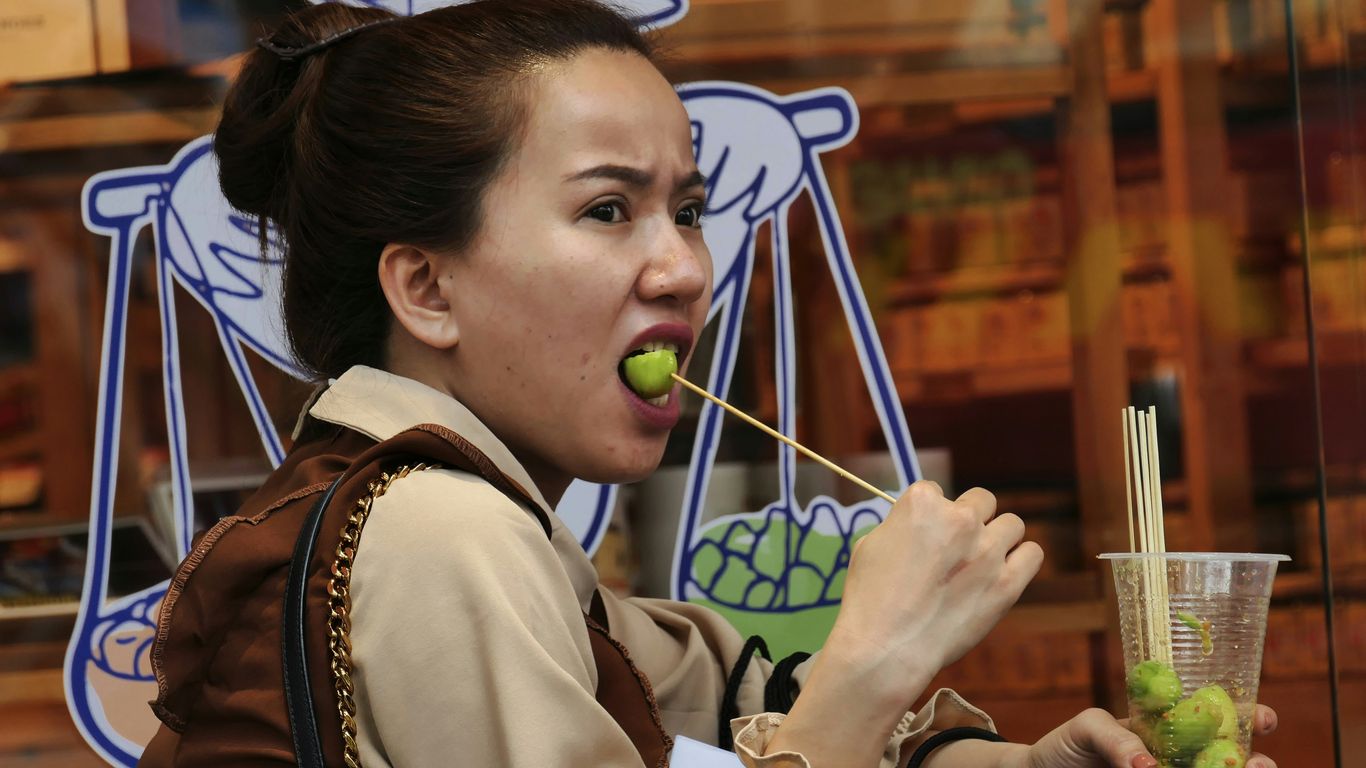 woman in white and brown school uniform holding green apple fruit