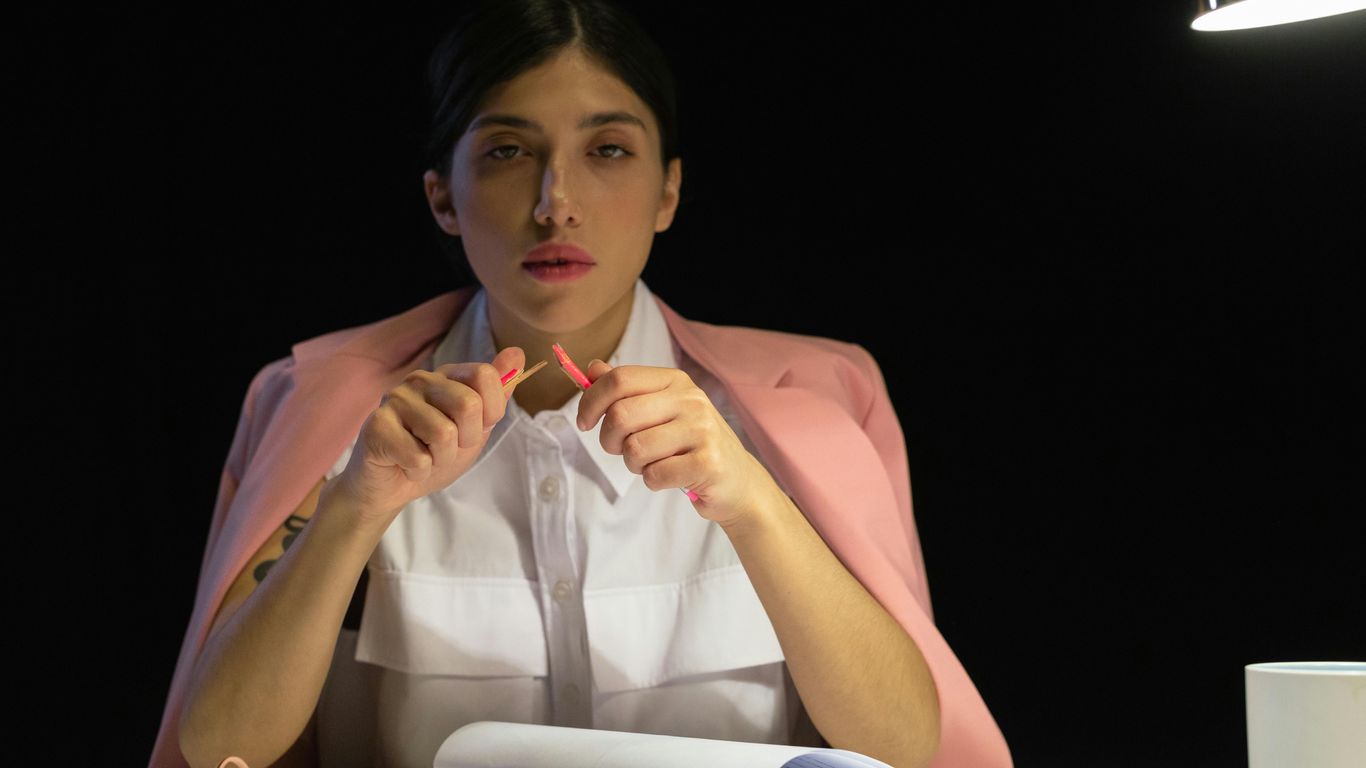 Person breaking a pencil in frustration at a desk.