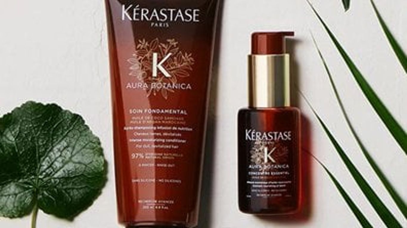 Kérastase haircare bottles with plant leaves on a neutral background.