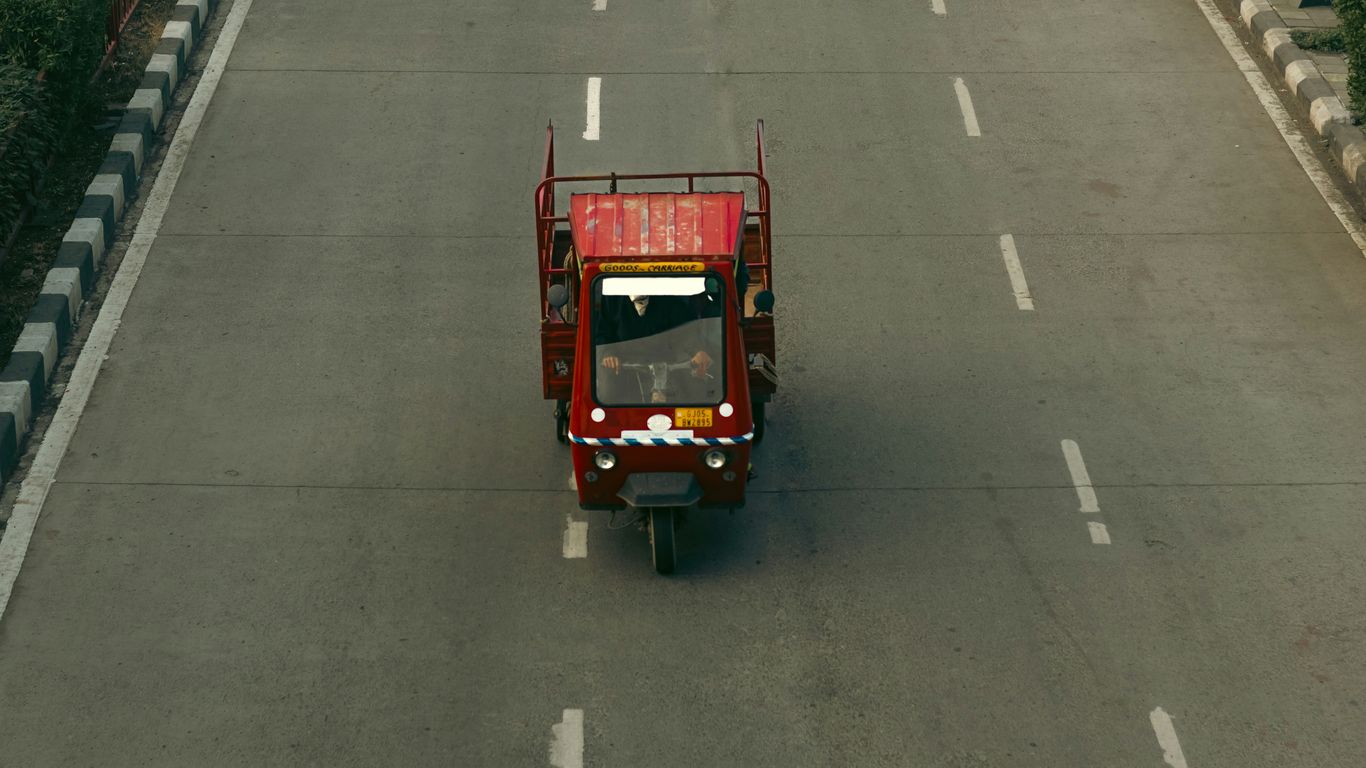 a red truck driving down a street next to a bridge