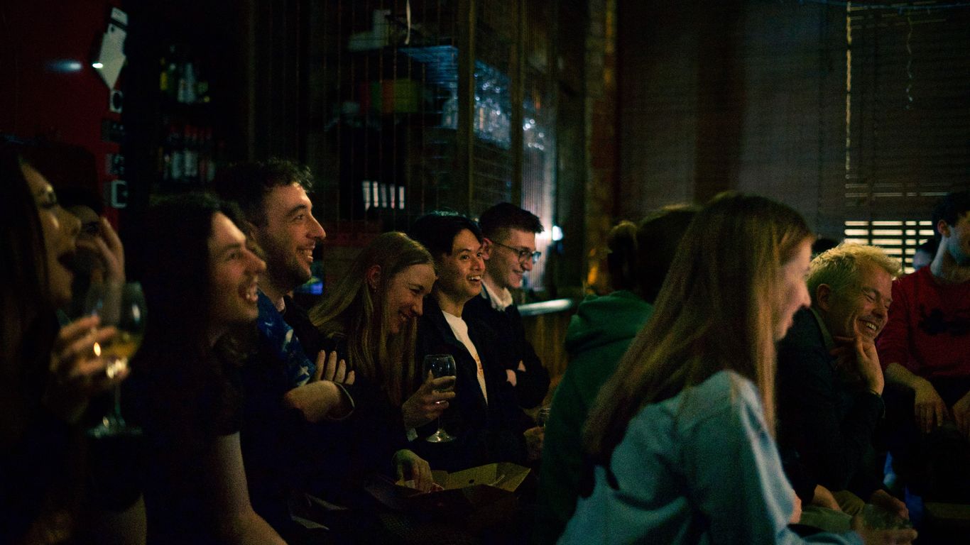 A group of people are laughing and enjoying themselves in a dimly lit venue.
