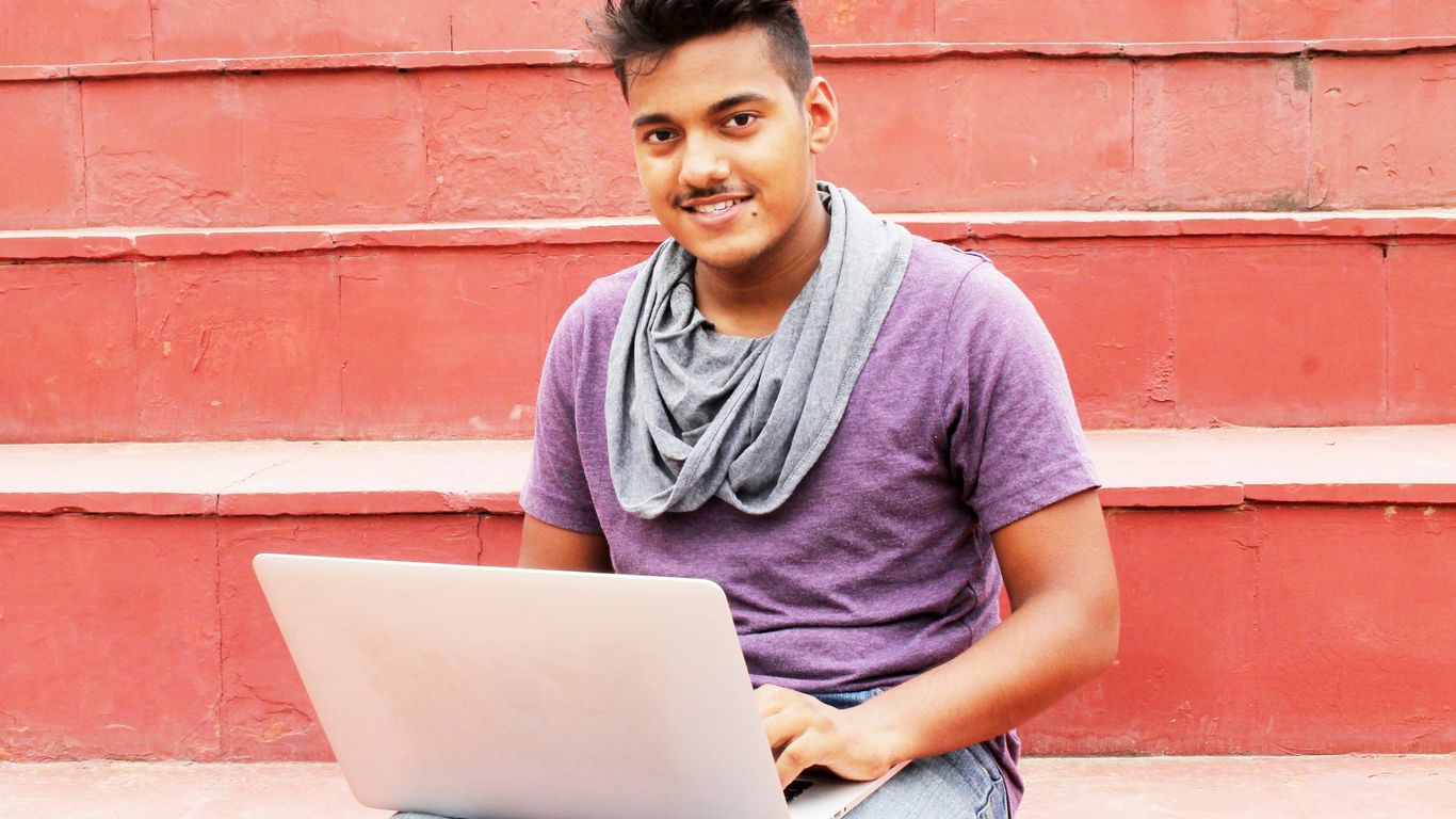 woman in purple shirt and blue denim jeans sitting on concrete bench