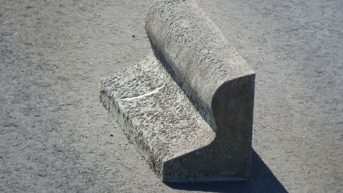 a concrete bench sitting on the side of a road