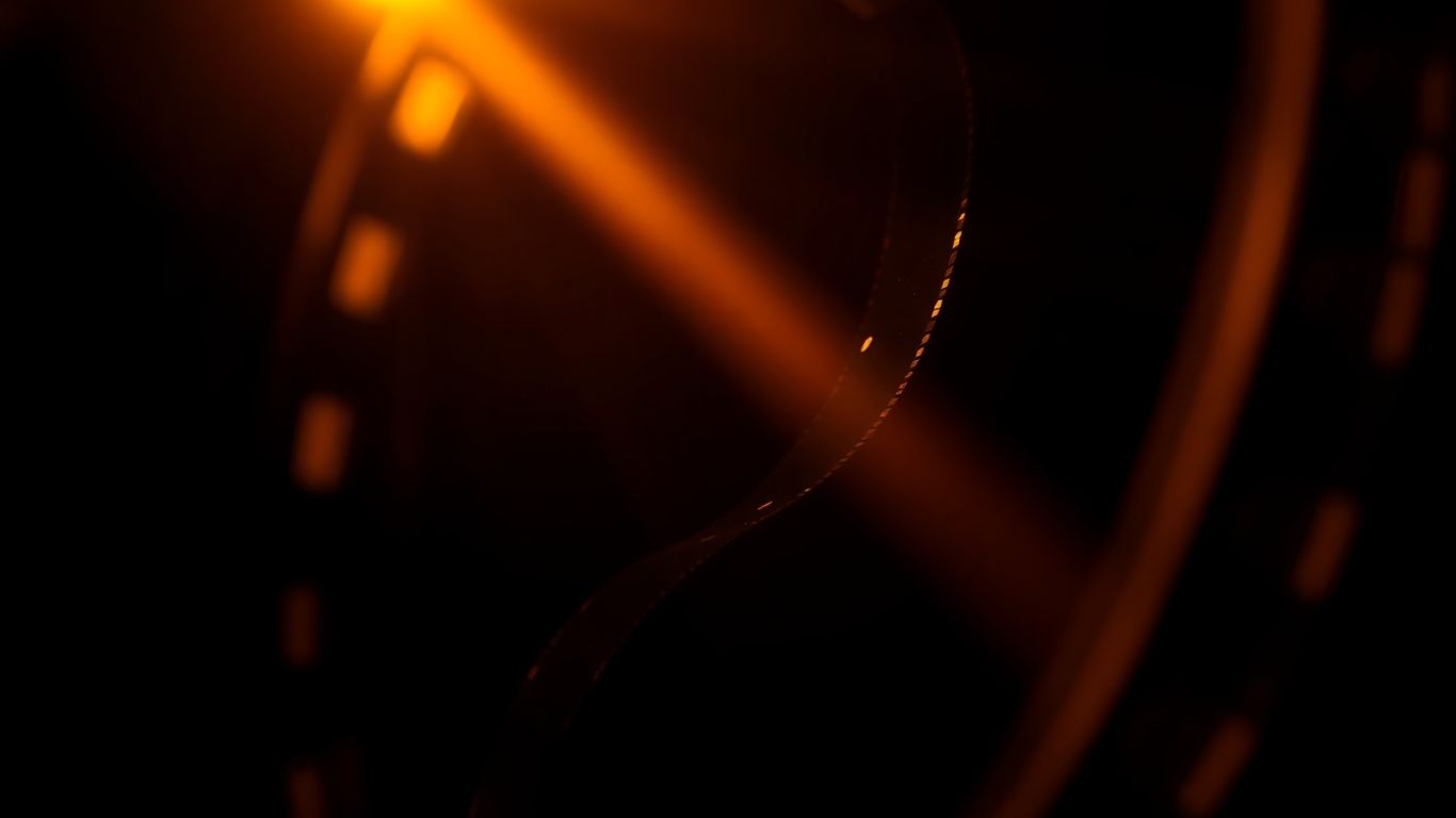 Film reel with light shining through perforations.