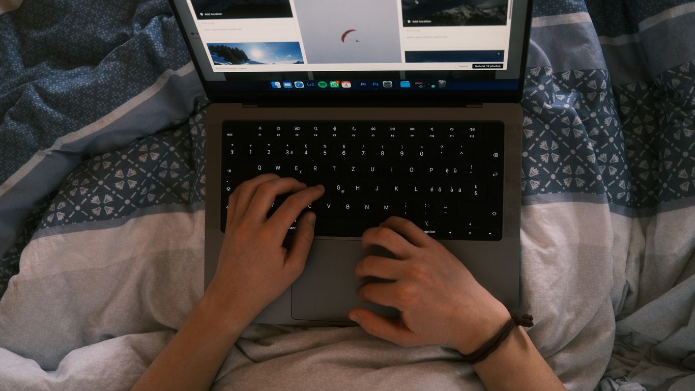 a person typing on a laptop on a bed