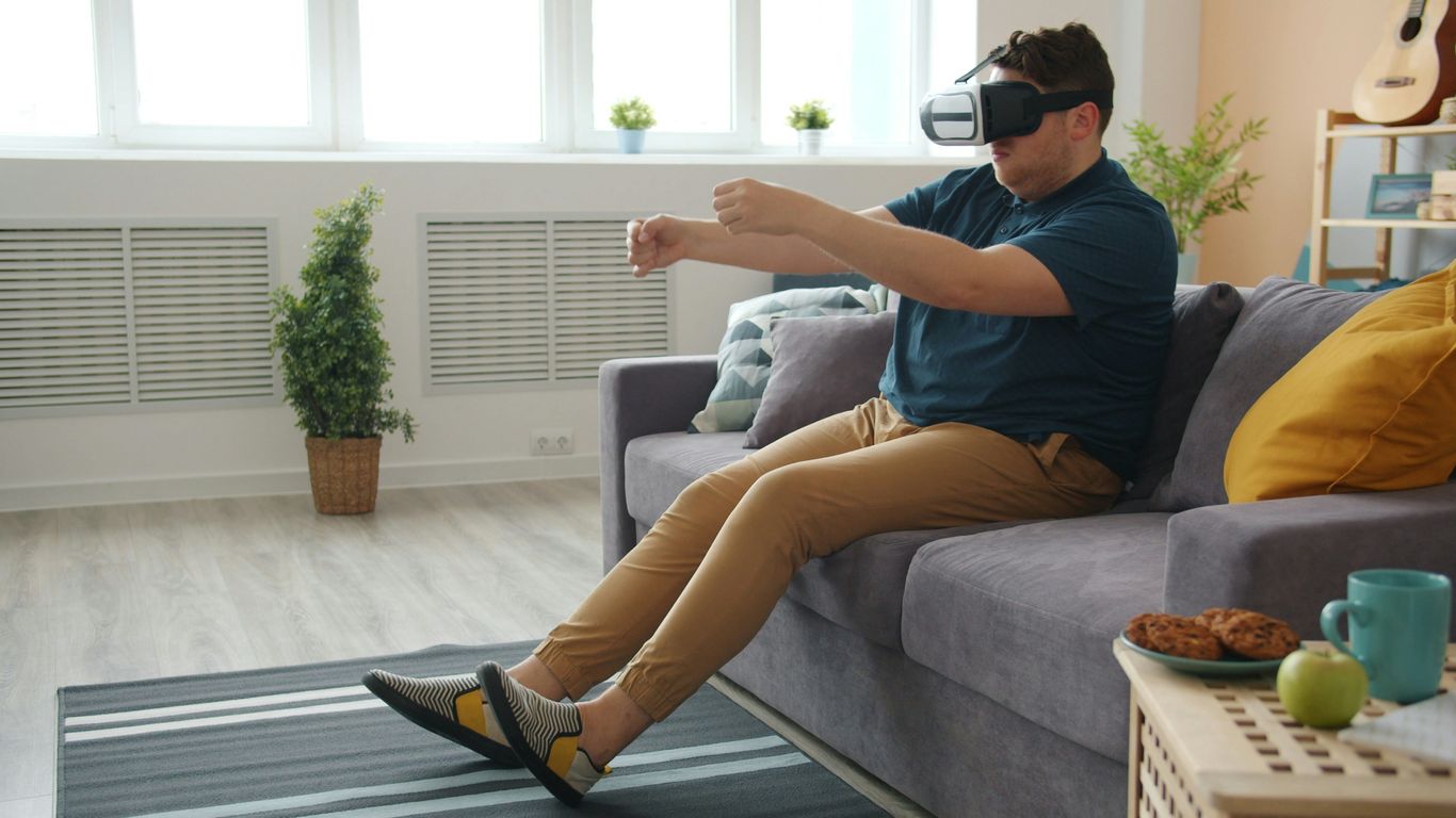Man wearing vr headset plays game on couch