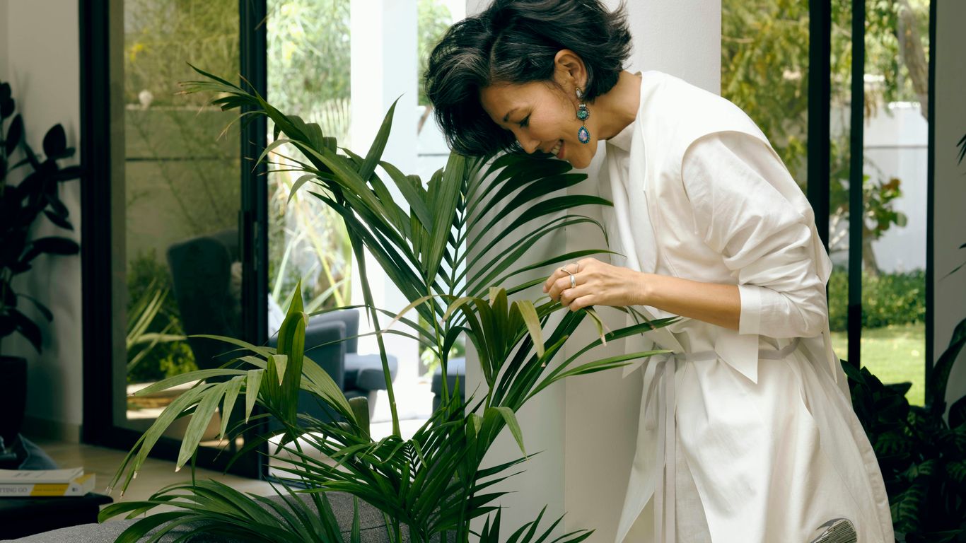 woman in white robe holding green plant