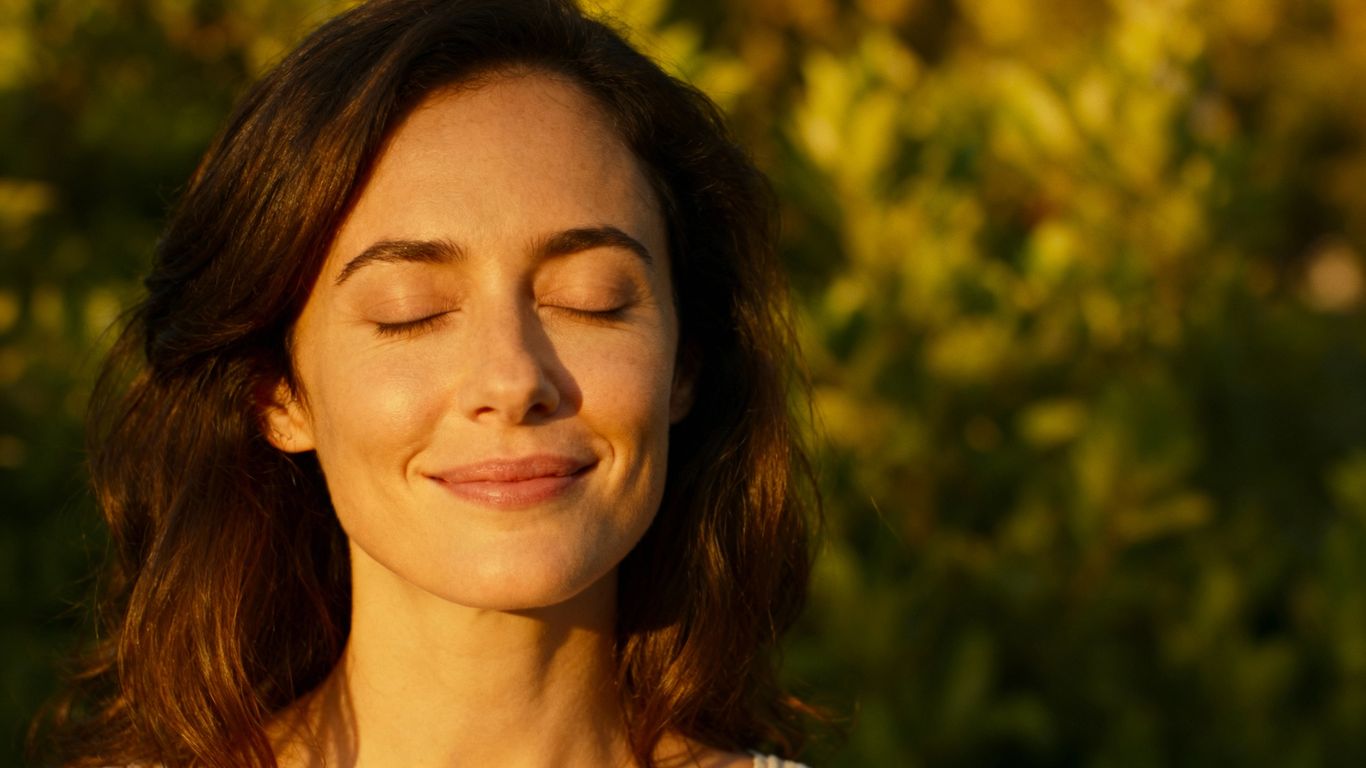 Woman practicing self-love with eyes closed and a smile.