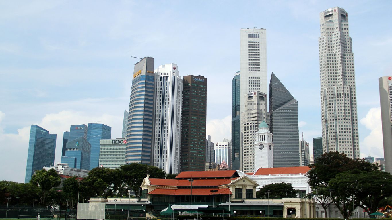white and gray concrete building near green grass field under white sky during daytime