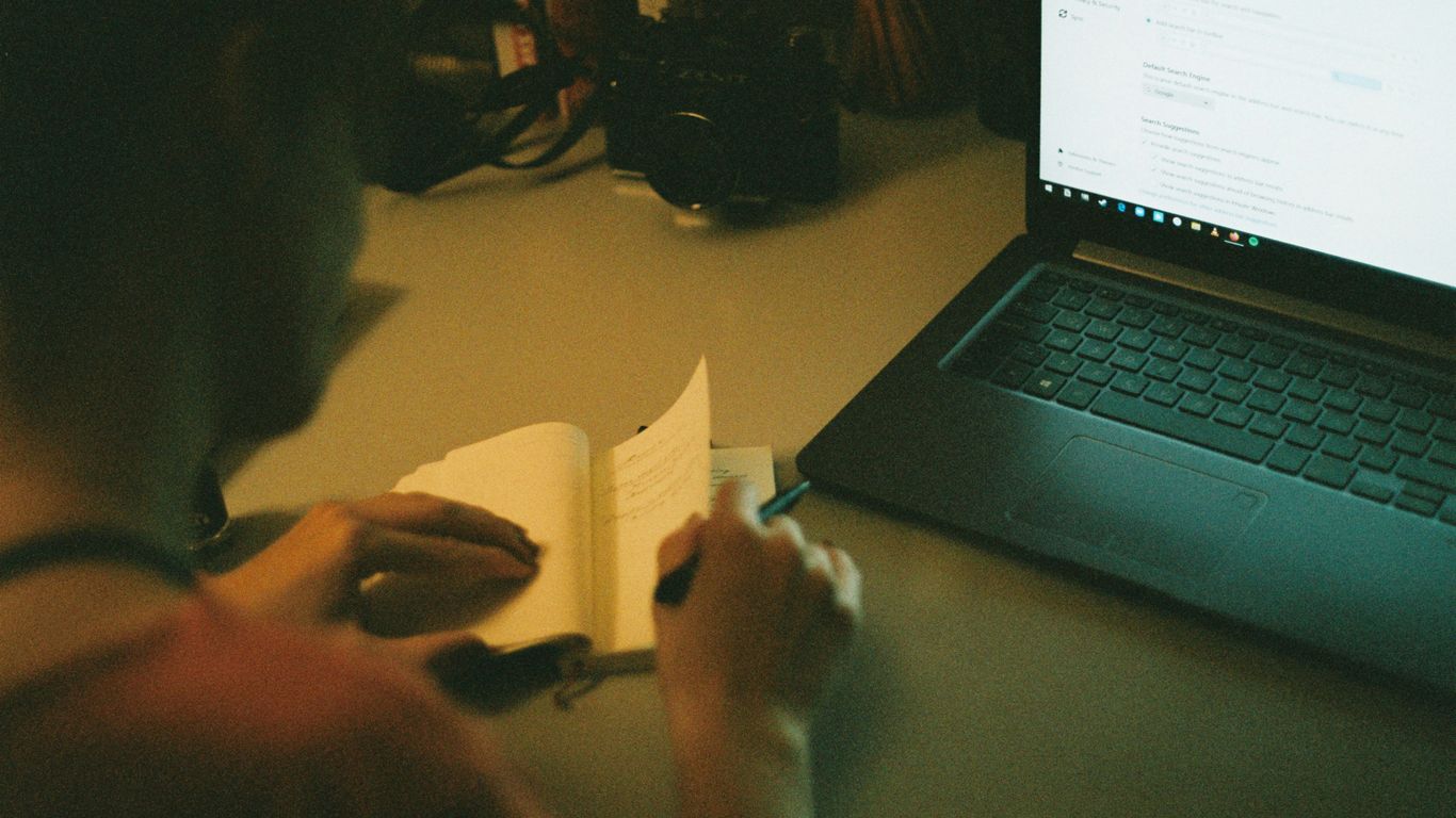 person holding white paper near black laptop computer