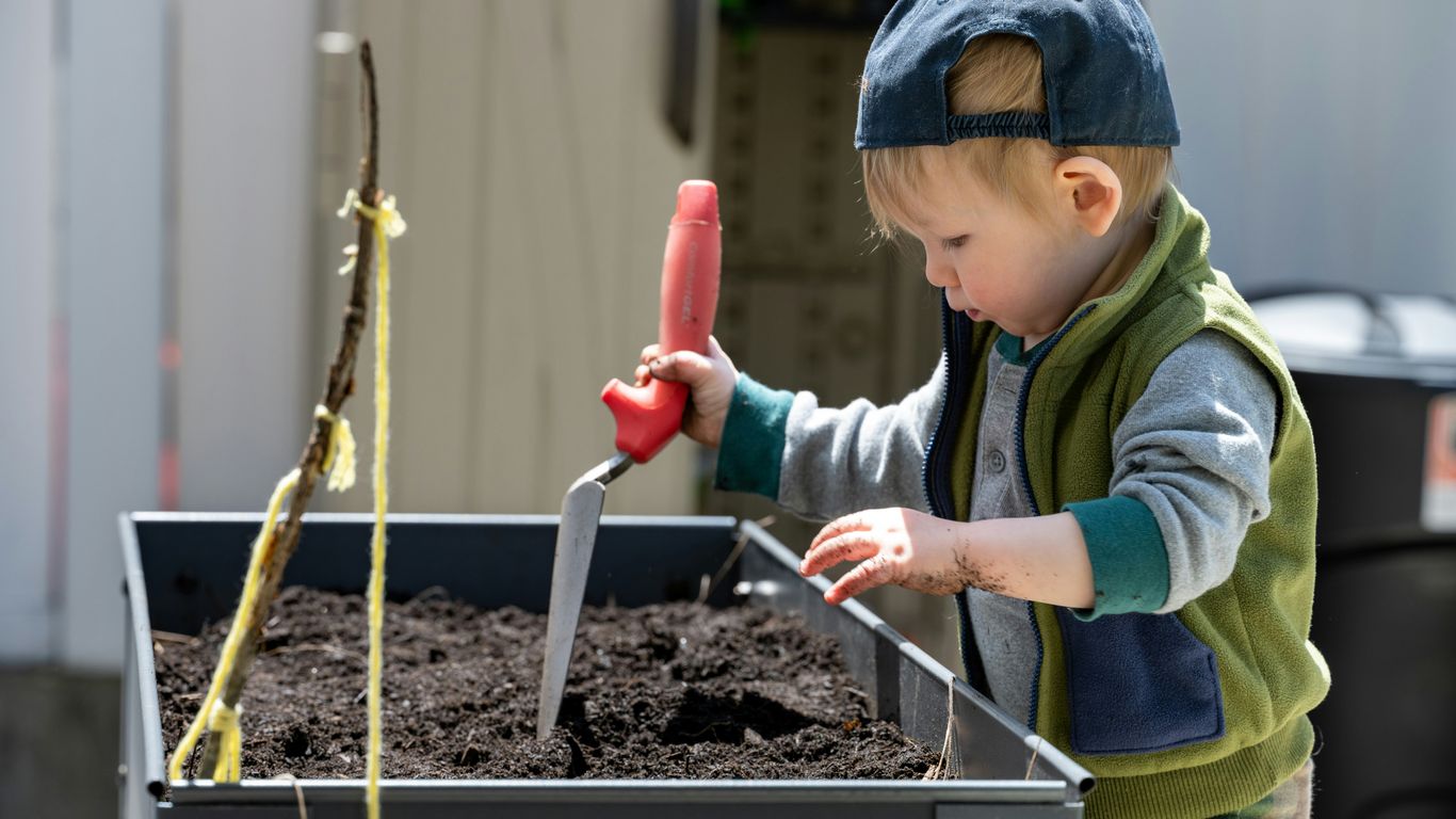 a young boy using a red tool to stir a substance in a container