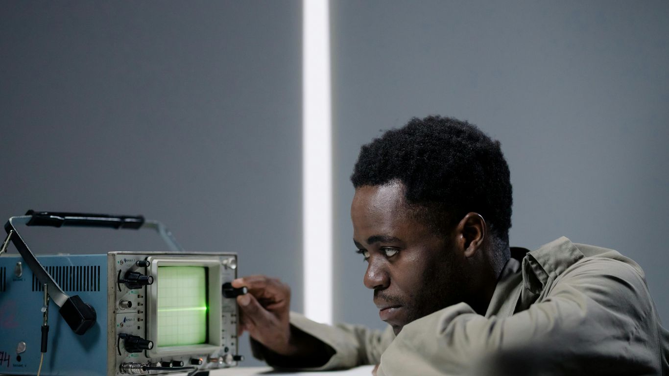 Person adjusting an oscilloscope, focused on the green display.