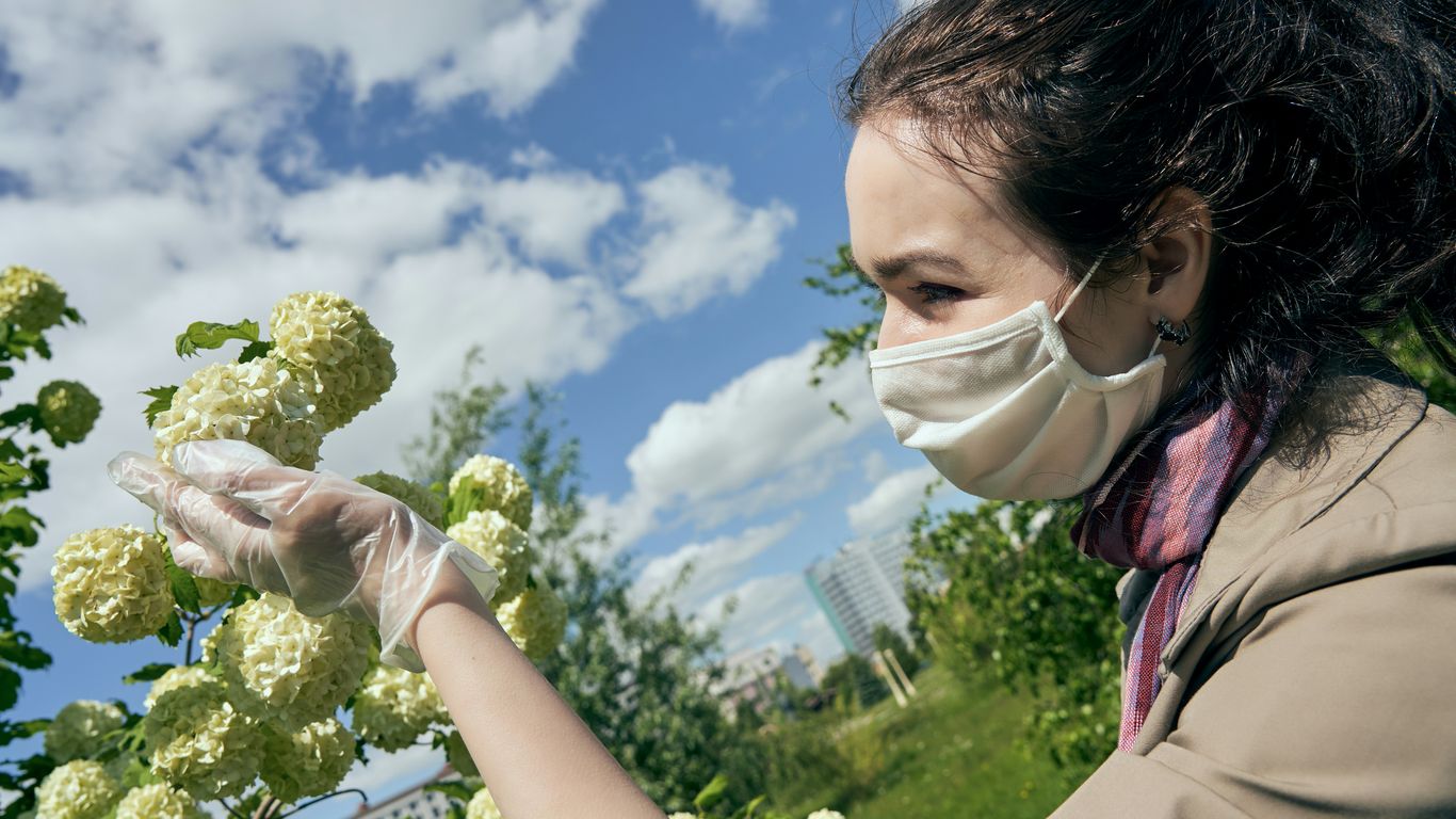 woman in pink shirt holding yellow flower during daytime