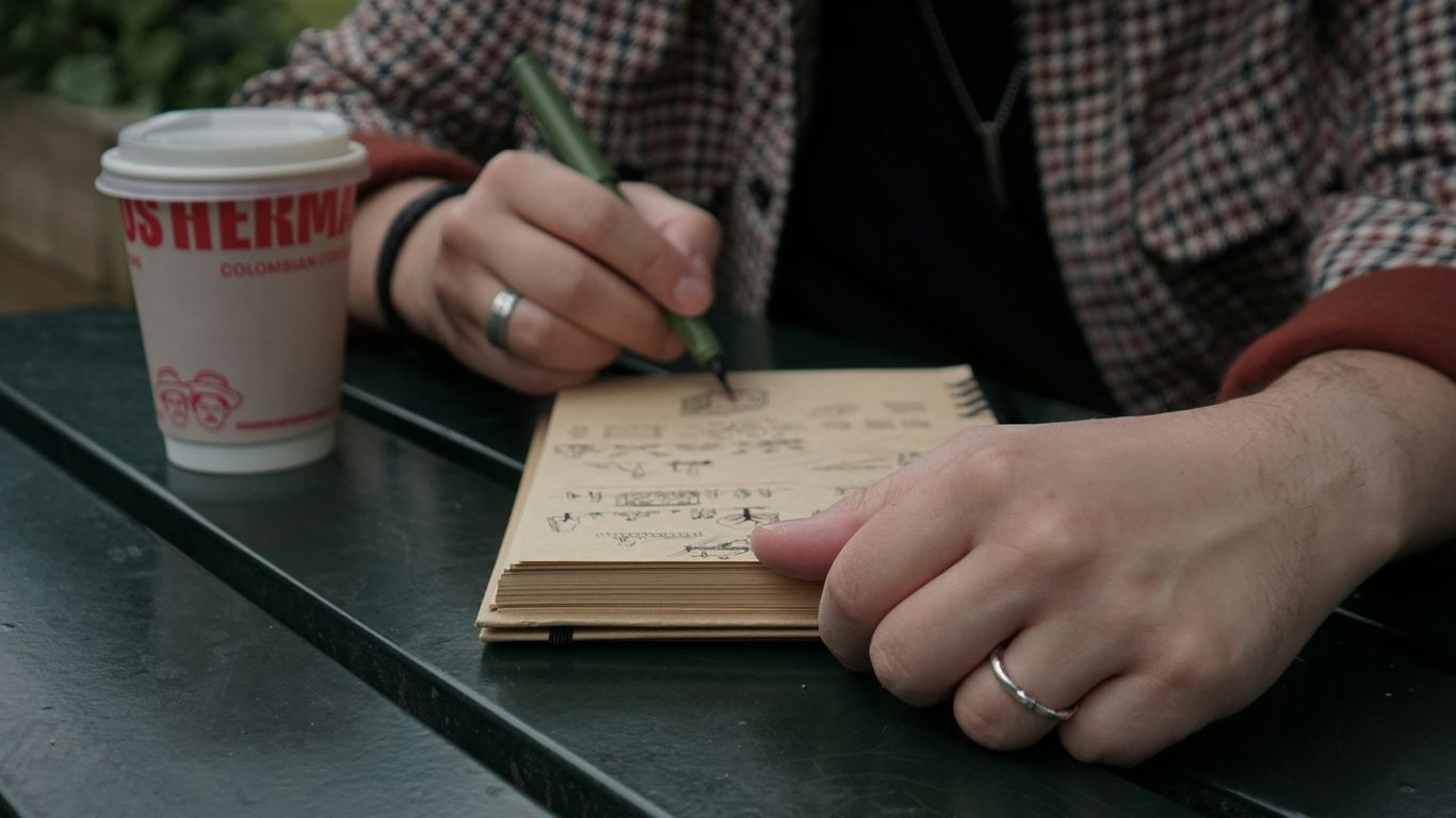 A person sitting at a table writing on a notebook