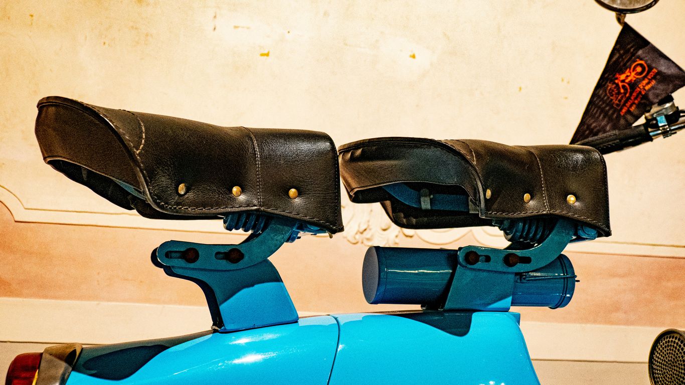 A vintage blue scooter with distinctive seat cushions.