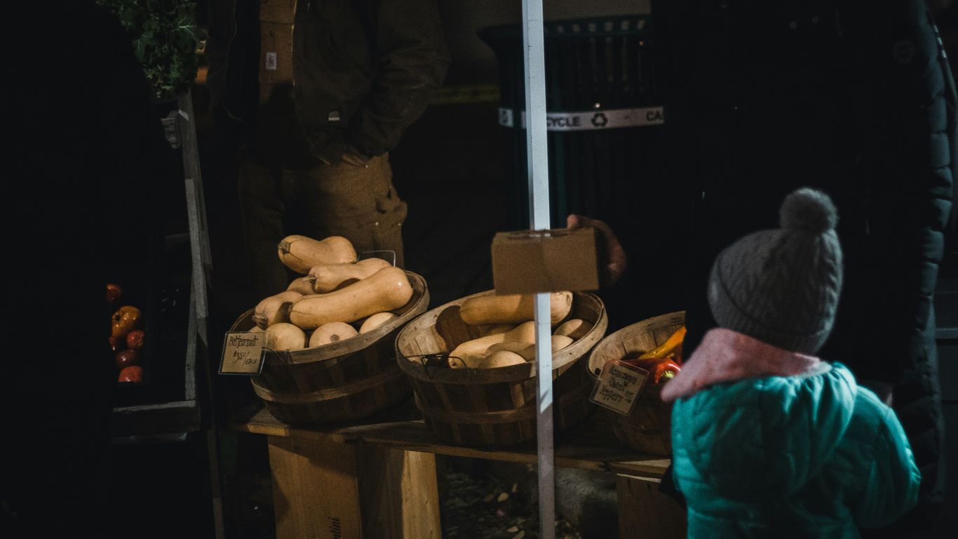 a little boy standing in front of a table full of food